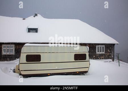 Camper - ein kleiner Minibus für Naturliebhaber in der Nähe einer alten schneebedeckten Hütte. Wetterbeobachtungsstelle auf dem Berg Pozhyzhevska Stockfoto
