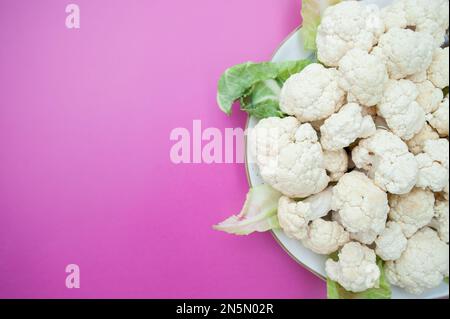 Blumenkohl blüht Nahaufnahme auf einer Platte, Draufsicht, rosafarbener Hintergrund, Platz für Text Stockfoto