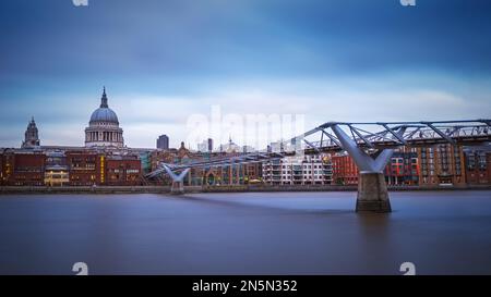 London, Großbritannien - Panoramablick auf die berühmte Millennium Bridge über die Themse und St. Paul's Cathedral in der Abenddämmerung mit klarem blauen Himmel Stockfoto