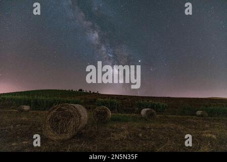 Nachtansicht mit der Milchstraße eines Heuballen-Feldes, Sizilien Stockfoto