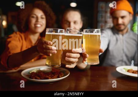 Eine Gruppe junger Leute, die vor der Kamera lächeln und mit Brille klappern Stockfoto