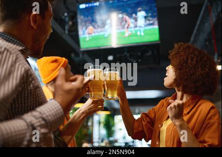 Glückliche Freunde, die Bier trinken und in der Sportbar zusammen jubeln Stockfoto