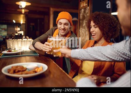 Glückliche Freunde, die Bier trinken, während sie sich an der Bar ausruhen Stockfoto