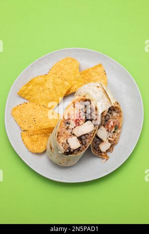 Mexikanischer Rindfleischburrito auf einem kleinen Teller mit Chips Nachos auf dem Teller Stockfoto