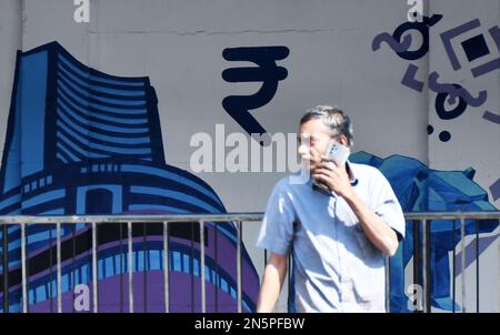 Mumbai, Maharashtra, Indien. 9. Februar 2023. Ein Mann, der mit einem Handy neben dem Graffiti der Bombay Stock Exchange (BSE) in Mumbai kommunizieren sah. Graffiti sind an der Wand gemalt, damit die Umgebung ordentlich und schön aussieht. (Kreditbild: © Ashish Vaishnav/SOPA Images via ZUMA Press Wire) NUR REDAKTIONELLE VERWENDUNG! Nicht für den kommerziellen GEBRAUCH! Stockfoto