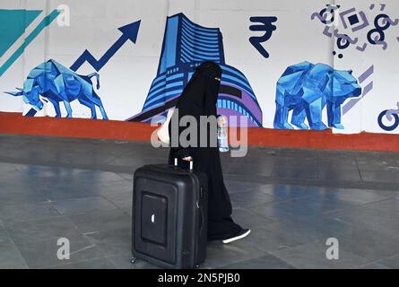 Mumbai, Maharashtra, Indien. 9. Februar 2023. Eine muslimische Frau mit einem Koffer geht an einem Graffiti der Bombay Stock Exchange (BSE) in Mumbai vorbei. Graffiti sind an der Wand gemalt, damit die Umgebung ordentlich und schön aussieht. (Kreditbild: © Ashish Vaishnav/SOPA Images via ZUMA Press Wire) NUR REDAKTIONELLE VERWENDUNG! Nicht für den kommerziellen GEBRAUCH! Stockfoto