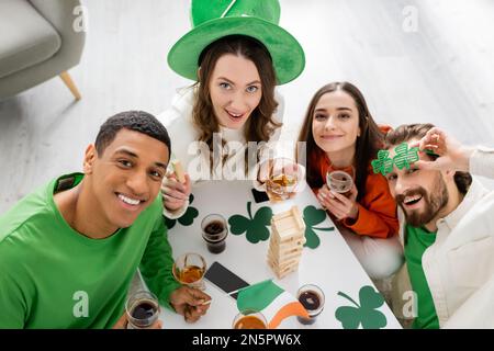 Blick von oben auf gemischte Freunde, die den saint patrick Day feiern und zu Hause in die Kamera schauen Stockfoto