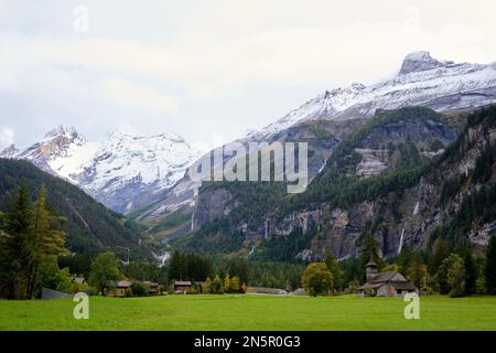 Selbst an einem bewölkten Tag sind die Berge über Kandersteg in der Schweiz majestätisch. Wasserfälle transportieren das Schmelzwasser von Schnee und Eis zum Talboden. Stockfoto