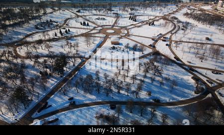 Ein kurvenreicher Radweg in einem Stadtpark. Stadtpark im Winter. Schnee liegt auf dem Boden. Luftaufnahmen. Stockfoto