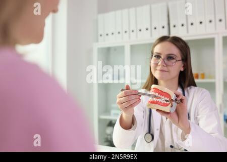 Die junge Zahnärztin erklärt ihrem Patienten die Regeln der Zahnpflege. Stockfoto