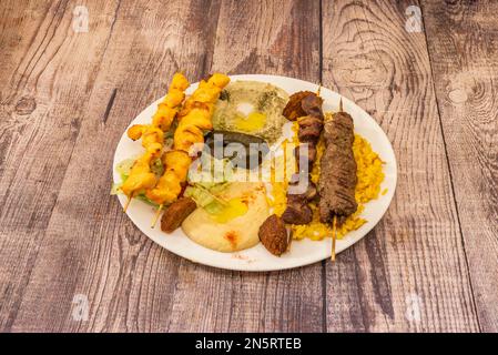 Speisekarte: Kebab-Platte mit maurischem Hähnchen, Lamm- und Rinderspießen, Hummus mit Paprika, Sarma-Bällen und Basmati-Reis Stockfoto