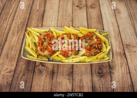 Ein neapolitanischer Mailänder mit gehackten Tomaten auf der Oberseite passierte im Ofen und mit Pommes frites Stockfoto