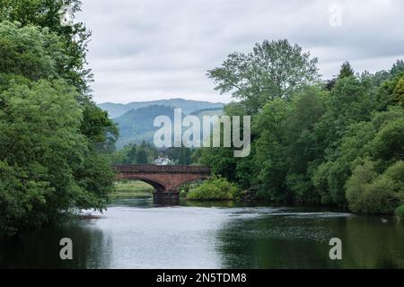 Callander Bridge und der Fluss Teith, mit Ben Ledi im Hintergrund, von der Fußgängerbrücke, die den Rob Roy Way Wanderweg nach Callander führt. Stockfoto