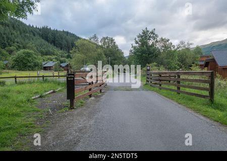 Sie nähern sich einem Holiday Chalet Park auf dem Rob Roy Way Wanderweg, der sich die National Cycle Route 7 auf dem Weg von Callander nach Strathyre teilt. Stockfoto