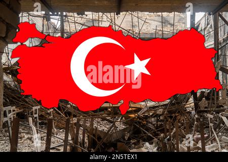 Erdbeben in der Türkei. Die türkische Nationalflagge in Form einer Karte der Türkei vor dem Hintergrund eines beschädigten Gebäudes Stockfoto