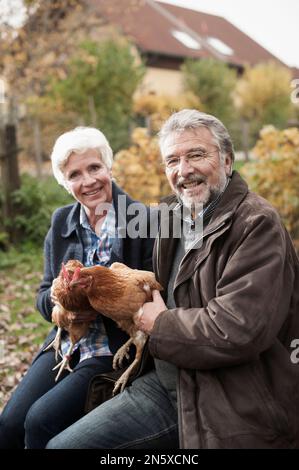 Reifes Paar, das Hühnervögel auf dem Bauernhof in Bayern hält Stockfoto