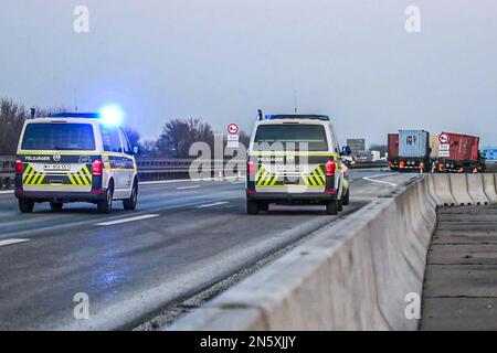 Kirchberg An Der Jagst, Deutschland. 09. Februar 2023. WIEDERHOLE DAS IN BESSERER QIALITY. Nach einem Unfall stehen Lastwagen (hinten) an der Autobahn, während die Militärpolizei die Straße absperrt. US-Militärtransporter, beladen mit Tonnen Sprengstoff und Raketen, die sich am Donnerstag auf der Autobahn 6 zwischen Heilbronn und Nürnberg übereinander stürzten. Laut Polizei wurden zwei Angehörige der Streitkräfte schwer verletzt. Obwohl einer der Transporter Feuer gefangen hatte, blieb die gefährliche Fracht nach einer ersten Bewertung unbeschädigt. Kredit: Marius Bulling/onw-images/Ostalb Network /dpa/Alamy Live News Stockfoto