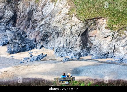 Zwei Personen sitzen auf einer Bank und bewundern die Aussicht vom Polurrian Hotel auf der Lizard in Cornwall Stockfoto