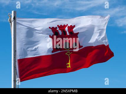 Gibraltar. 5. September 2022 Blick aus dem niedrigen Winkel auf die Flagge von Gibraltar - das britische Überseegebiet, das in starkem Wind gegen einen blauen Himmel fliegt. Stockfoto