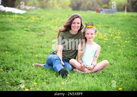 Mutter und Tochter sitzen zusammen auf einer Löwenwiebelwiese. Stockfoto