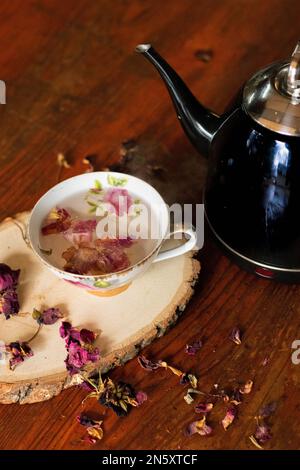Schwarzer Teekessel neben einer Teetasse mit rosa Blumen Stockfoto