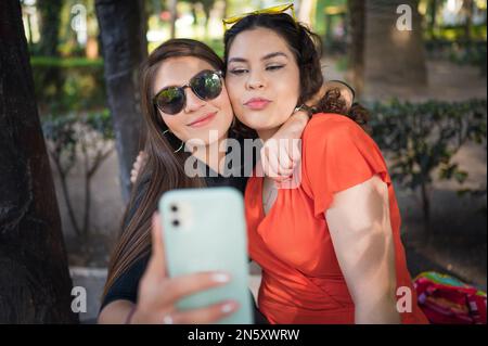 Zwei junge lateinische Freundinnen, die im Wald spazieren gehen Stockfoto