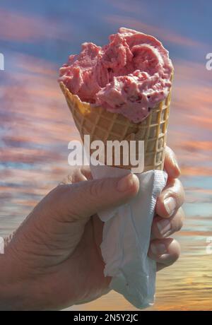 Ein Mann hält in der Hand ein Eis am Stiel in einem Waffelglas, in einer Serviette verpackt Stockfoto