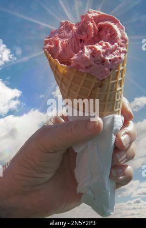 Ein Mann hält in der Hand ein Eis am Stiel in einem Waffelglas, in einer Serviette verpackt Stockfoto