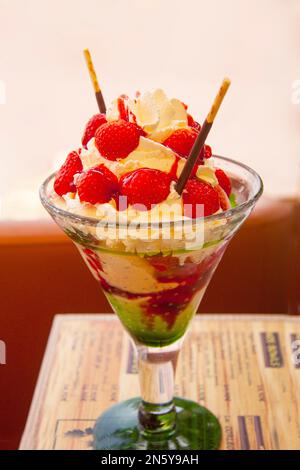 Köstliches Eis mit frischen Erdbeeren und Schlagsahne, serviert in einer Glasschüssel in einem Restaurant. Stockfoto