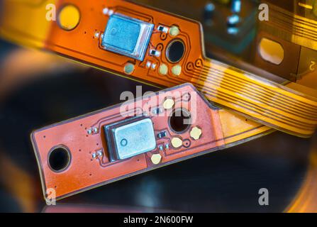 Wunderschöne flexible elektronische gedruckte Schaltungen auf gelben und orangefarbenen Streifen auf schwarzem, verschwommenem Hintergrund. Nahaufnahme von biegsamen Leiterplatten oder kleinen Bauteilen. Stockfoto