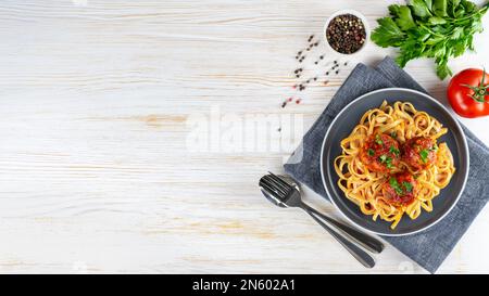 Hausgemachte Spaghetti mit Tomatensoße, Fleischklößchen und Gewürzen auf weißem Hintergrund. Leckere gekochte Pasta und Fleischbällchen mit Hackfleisch, Essen in Stockfoto