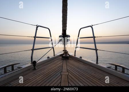 Der Bug einer Segelyacht zeigt in den Sonnenuntergang auf einem ruhigen Meer in der kroatischen Inselgruppe Stockfoto