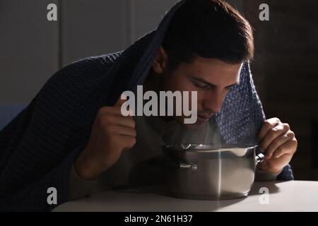 Ein Mann mit Karomuster inhaliert über dem Saucetopf im Haus Stockfoto