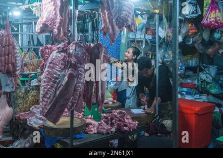 Ein glückliches kambodschanisches Paar verkauft nachts rohes Fleisch auf dem Hauptmarkt für Gemüse und Fleisch. Phsar Dumkor, Phnom Penh, Kambodscha. © Kraig Stockfoto