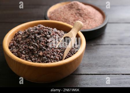 Schüsseln mit schwarzem Salz auf Holztisch, Nahaufnahme Stockfoto