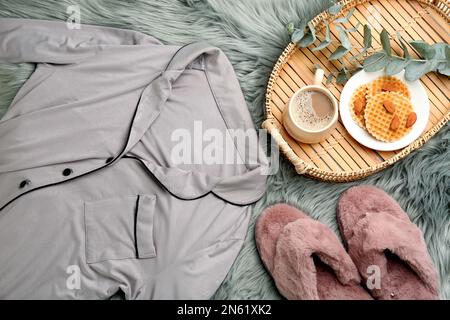 Flach liegend mit flauschigen Hausschuhen und Schlafanzug auf flauschigem Teppich. Bequemes Heim-Outfit Stockfoto