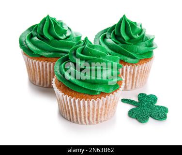 Leckere Cupcakes für St. Patrick's Day und Klee isoliert auf weißem Hintergrund Stockfoto