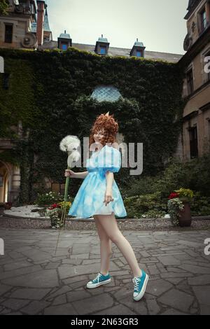 Schöne junge Frau in blauem Kleid mit Wolken in einem Schloss Stockfoto