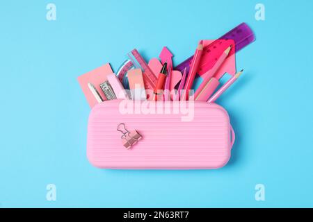 Federmäppchen mit verschiedenen Schreibwaren auf hellblauem Hintergrund, Draufsicht. Zurück in die Schule Stockfoto