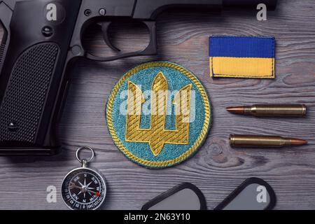 MYKOLAIV, UKRAINE - 19. SEPTEMBER 2020: Flacher Laienaufbau mit ukrainischer Militärausrüstung auf grauem Holztisch Stockfoto