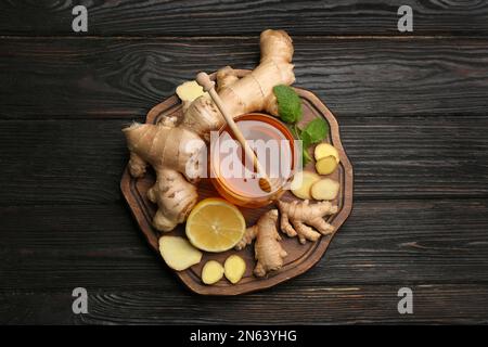 Ingwer und andere natürliche Kaltmittel auf schwarzem Holztisch, Draufsicht Stockfoto