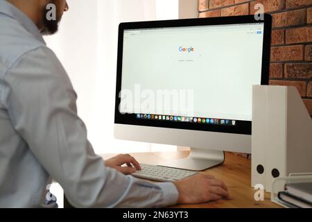 MYKOLAIV, UKRAINE - 27. OKTOBER 2020: Mann mit Google-Suchmaschine auf Apple iMac PC am Tisch in Innenräumen, Nahaufnahme Stockfoto
