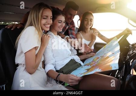 Glückliche Freunde mit Karte im Auto auf dem Road Trip Stockfoto