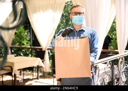 Kellner mit gepackten Speisen zum Mitnehmen im Restaurant. Gastronomie während der Coronavirus-Quarantäne Stockfoto