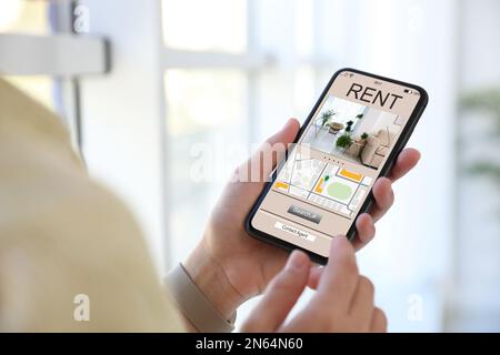 Eine Frau, die auf der Website des Mietobjekts nach einer Wohnung sucht, per Smartphone, Nahaufnahme Stockfoto