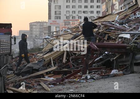 Antakya, Türkei. 09. Februar 2023. Zwei Leute ziehen Holz aus einem Berg von Schutt in Antakya. Mehr als drei Tage nach der Erdbebenkatastrophe ist die Hoffnung auf mehr Überlebende verloren. Unter den Tausenden von eingestürzten Gebäuden im türkisch-syrischen Grenzgebiet gibt es wahrscheinlich immer noch Zehntausende von Erdbebenopfern. Kredit: Anne Pollmann/dpa/Alamy Live News Stockfoto