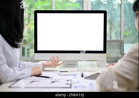 Zwei professionelle asiatische Buchhalterinnen oder Finanzanalysten, die im Büro zusammenarbeiten, PC-Computer-Weißbildschirmmodell. Stockfoto