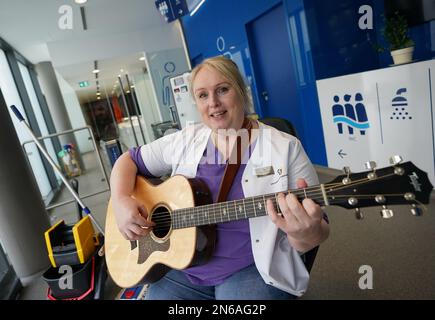 Hamburg, Deutschland. 09. Februar 2023. Stefanie Ansul-Weissner, Reinigungskraft der STR Stadtteilreinigungsgesellschaft mbH, spielt Gitarre und singt ein Lied auf der öffentlichen Toilette am Niederhafen. In Hamburg, direkt an der Elbpromenade, gibt es einen ruhigen kleinen Ort, der dank einer musikalischen Toilettenwächter überhaupt nicht so ruhig ist und auch gute Laune hat. (Zu dpa: 'Gute Laune beim Wiegenmachen - Hamburger Toilettenfrau spielt Gitarre') Credit: Marcus Brandt/dpa/Alamy Live News Stockfoto