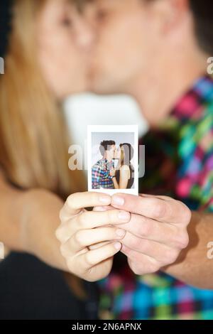 Küssen im Quadrat. Ein junges küssendes Paar, das ein Foto von einem küssenden Paar hält. Stockfoto