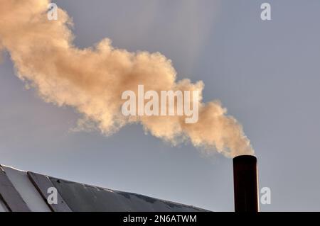 Rauch kommt aus dem Schornstein der Bourgeoisie, der Ofen wird erhitzt. Stockfoto